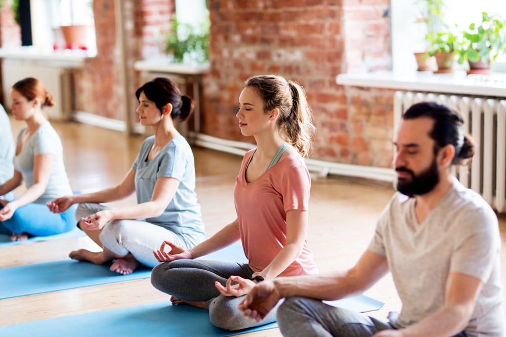 fitness, yoga and healthy lifestyle concept - group of people meditating in lotus pose at studio