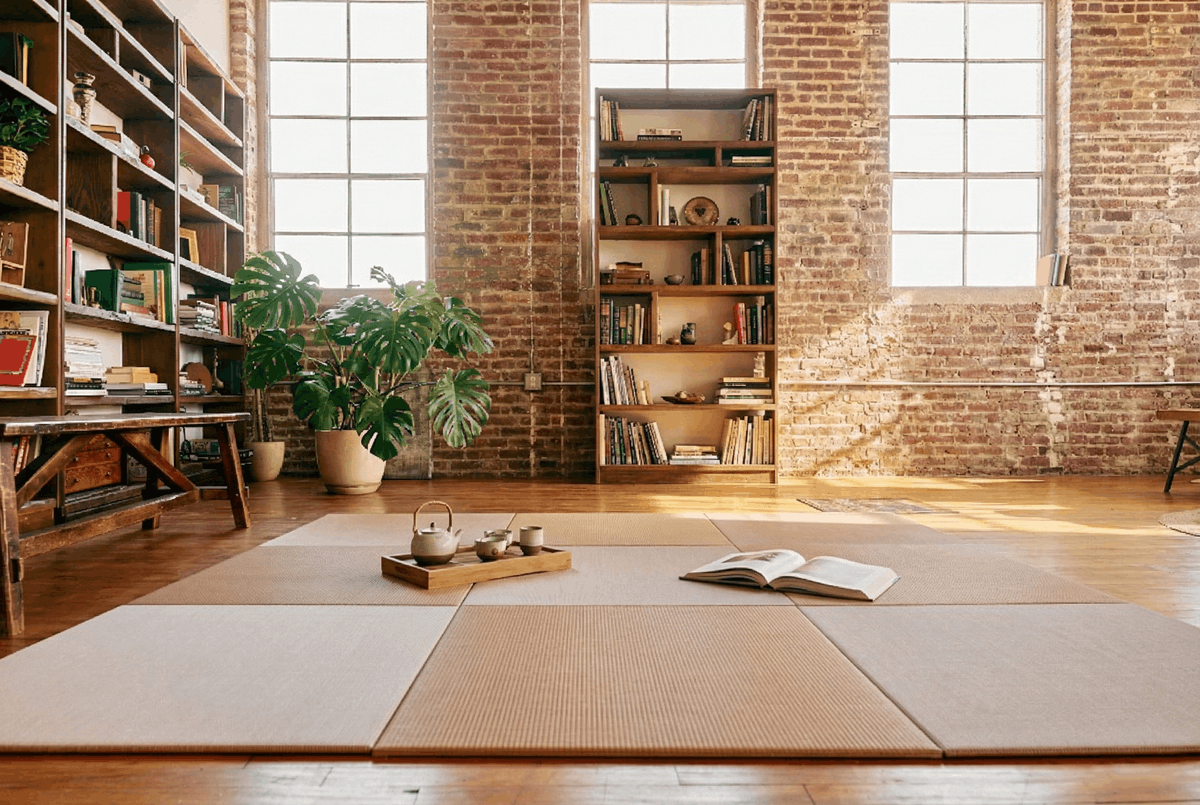 A bright interior space with tatami mats, brick walls, and wooden bookshelves